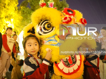 Children pose for a photo with lion dancers at the ancient town of Xunxian in Hebi, China, on September 24, 2024. (