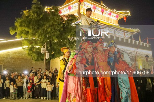 Stilt performers perform for tourists at the ancient town of Xunxian County in Hebi, China, on September 24, 2024. 