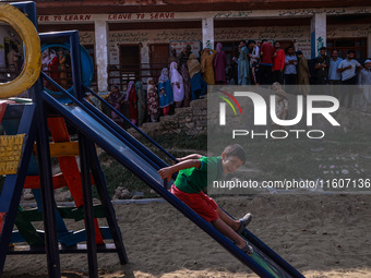 Kids play as people wait to cast their votes in the second phase of Assembly elections in Beerwah, Jammu and Kashmir, India, on September 25...