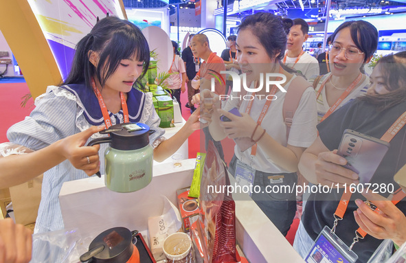 Visitors buy drinks at the Malaysian booth at the 21st China-Asean Expo in Nanning, Guangxi Zhuang Autonomous Region, China, on September 25...