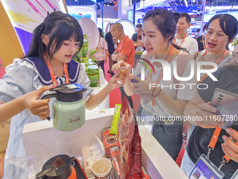 Visitors buy drinks at the Malaysian booth at the 21st China-Asean Expo in Nanning, Guangxi Zhuang Autonomous Region, China, on September 25...