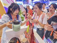 Visitors buy drinks at the Malaysian booth at the 21st China-Asean Expo in Nanning, Guangxi Zhuang Autonomous Region, China, on September 25...