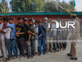 An Indian policeman stands guard as voters queue to cast their ballots at a polling station during the second phase of assembly elections in...