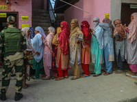 An Indian security personnel stands guard as women voters queue to cast their ballots at a polling station during the second phase of assemb...