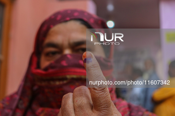 A woman shows her ink-marked finger after casting her ballot at a polling station during the second phase of assembly elections in Srinagar,...