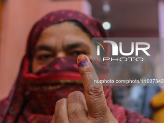 A woman shows her ink-marked finger after casting her ballot at a polling station during the second phase of assembly elections in Srinagar,...