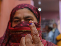 A woman shows her ink-marked finger after casting her ballot at a polling station during the second phase of assembly elections in Srinagar,...