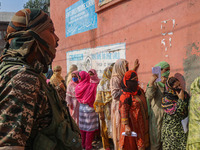 An Indian security personnel stands guard as women voters queue to cast their ballots at a polling station during the second phase of assemb...