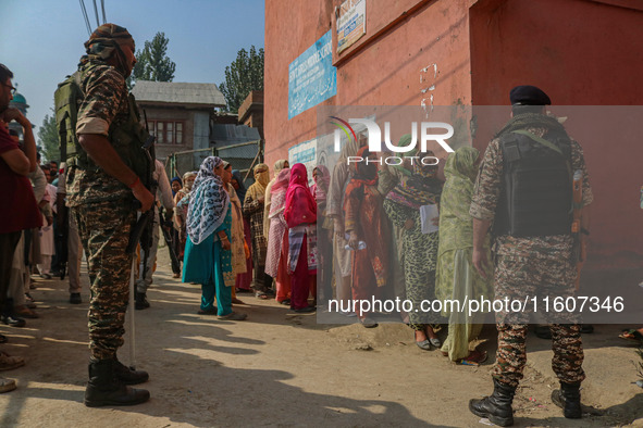 Indian security personnel stand guard as women voters queue to cast their ballots at a polling station during the second phase of assembly e...