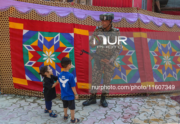 An Indian security personnel gestures towards children during the second phase of assembly elections in Srinagar, Jammu and Kashmir, on Sept...