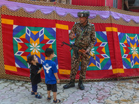 An Indian security personnel gestures towards children during the second phase of assembly elections in Srinagar, Jammu and Kashmir, on Sept...