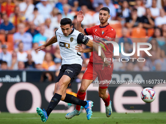 Cesar Tarrega of Valencia CF competes for the ball with Raul of CA Osasuna during the LaLiga EA Sports match between Valencia CF and CA Osas...