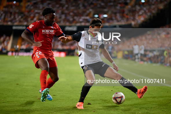 Jesus Vazquez (R) of Valencia CF competes for the ball with Boyomo of CA Osasuna during the LaLiga EA Sports match between Valencia CF and C...