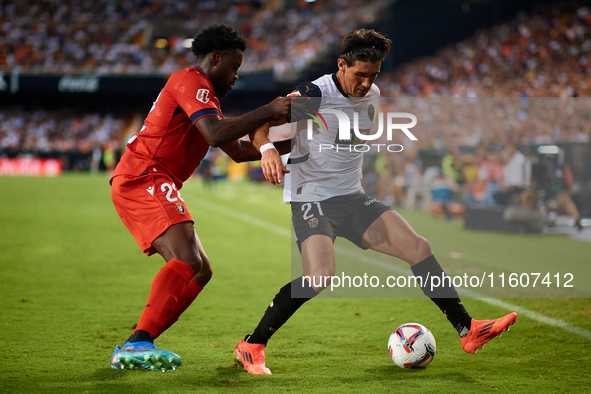 Jesus Vazquez (R) of Valencia CF competes for the ball with Boyomo of CA Osasuna during the LaLiga EA Sports match between Valencia CF and C...