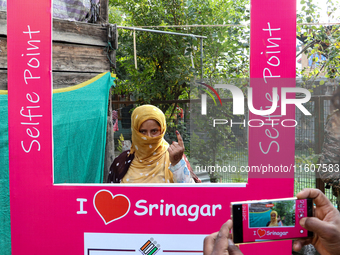 A woman voter poses for a picture after casting her vote at a polling station during the second phase of assembly elections in Srinagar, Ind...