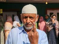 A man poses for a picture after casting his vote at a polling station during the second phase of assembly elections in Srinagar, Indian Admi...