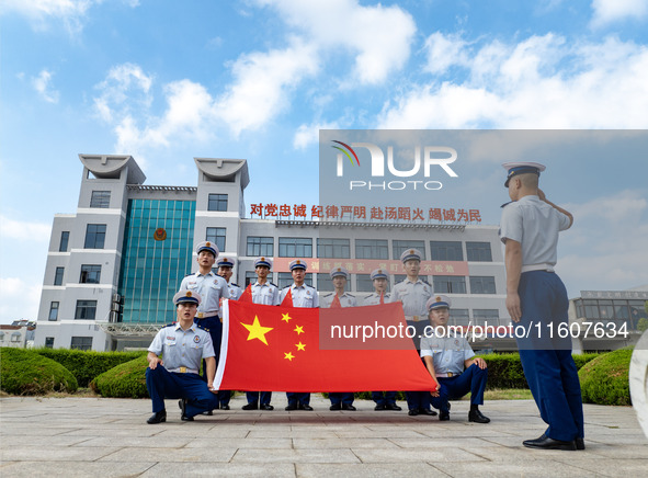 Firefighters pose for a photo with the national flag at the Fire and Rescue Brigade in Xinghua, China, on September 25, 2024. 