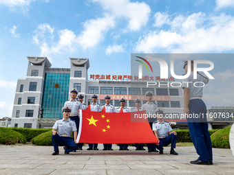 Firefighters pose for a photo with the national flag at the Fire and Rescue Brigade in Xinghua, China, on September 25, 2024. (