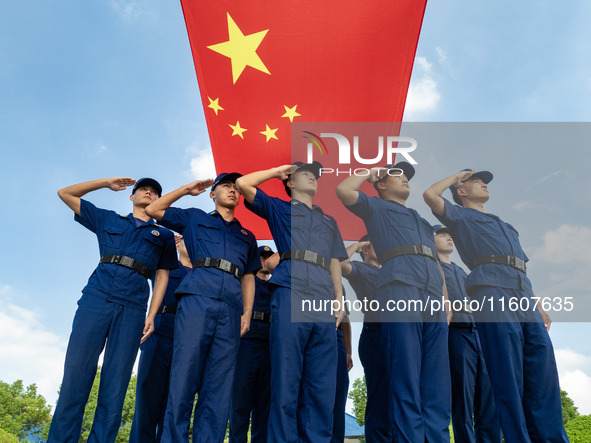 Firefighters pose for a photo with the national flag at the Fire and Rescue Brigade in Xinghua, China, on September 25, 2024. 