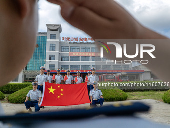 Firefighters pose for a photo with the national flag at the Fire and Rescue Brigade in Xinghua, China, on September 25, 2024. (