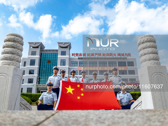 Firefighters pose for a photo with the national flag at the Fire and Rescue Brigade in Xinghua, China, on September 25, 2024. 