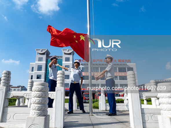 Firefighters pose for a photo with the national flag at the Fire and Rescue Brigade in Xinghua, China, on September 25, 2024. 