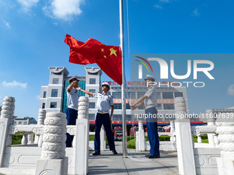 Firefighters pose for a photo with the national flag at the Fire and Rescue Brigade in Xinghua, China, on September 25, 2024. (