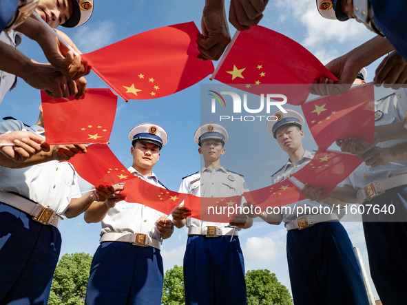 Firefighters pose for a photo with the national flag at the Fire and Rescue Brigade in Xinghua, China, on September 25, 2024. 