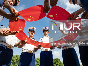 Firefighters pose for a photo with the national flag at the Fire and Rescue Brigade in Xinghua, China, on September 25, 2024. (