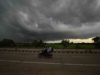 A man rides a bike as dark clouds loom over the sky in Morigaon District of Assam, India, on September 25, 2024. (