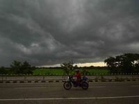 A man rides a bike as dark clouds loom over the sky in Morigaon District of Assam, India, on September 25, 2024. (