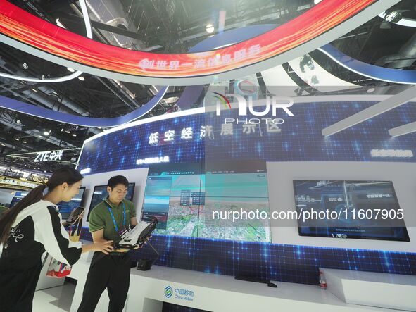 Visitors visit the ''5G+ Connected drone'' at the booth of China Mobile at the 2024 China International Information and Communications Exhib...