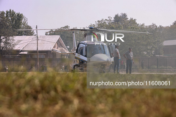 Officials stand near a helicopter used by National Conference Vice President Omar Abdullah during assembly election campaigning in Baramulla...