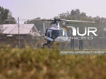 Officials stand near a helicopter used by National Conference Vice President Omar Abdullah during assembly election campaigning in Baramulla...