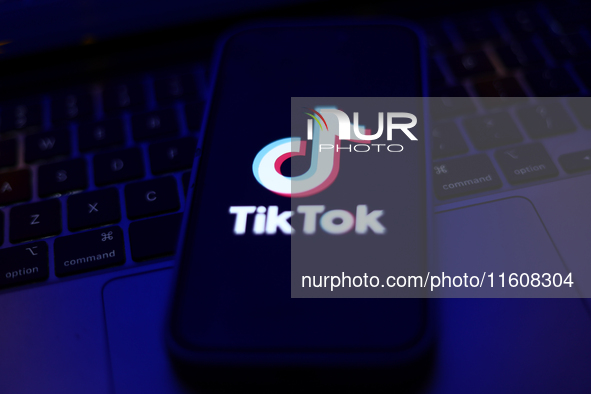 TikTok logo displayed on a phone screen and a laptop keyboard are seen in this illustration photo taken in Krakow, Poland on September 25, 2...