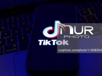 TikTok logo displayed on a phone screen and a laptop keyboard are seen in this illustration photo taken in Krakow, Poland on September 25, 2...