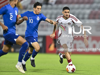 Ibrahim Mohammadali (R) of Qatar battles for the ball with Jonan Tan (L) of Singapore during the 2025 AFC U20 Asian Cup Qualifiers Group J m...