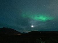 The Aurora Borealis, commonly known as the Northern Lights, are seen with the half-moon in the sky near Tromso, Norway, on September 25, 202...