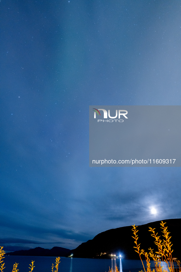 The Aurora Borealis, commonly known as the Northern Lights, are seen with the half-moon in the sky near Tromso, Norway, on September 25, 202...