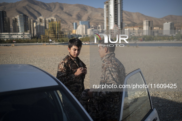 Two Iranian schoolboys wear Islamic Revolutionary Guard Corps (IRGC) military uniforms while preparing to take part in a war game, which is...