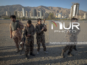 Two Iranian schoolboys wear Islamic Revolutionary Guard Corps (IRGC) military uniforms and hold AK-45 rifles while preparing to take part in...