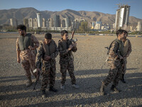 Two Iranian schoolboys wear Islamic Revolutionary Guard Corps (IRGC) military uniforms and hold AK-45 rifles while preparing to take part in...