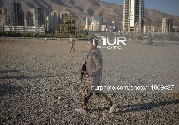 An Iranian schoolboy wears an Islamic Revolutionary Guard Corps (IRGC) military uniform and carries an AK-45 rifle while preparing to take p...