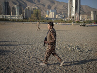 An Iranian schoolboy wears an Islamic Revolutionary Guard Corps (IRGC) military uniform and carries an AK-45 rifle while preparing to take p...