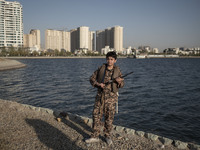 An Iranian schoolboy wearing an Islamic Revolutionary Guard Corps (IRGC) military uniform poses for a photograph as he holds an AK-45 rifle,...