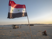 A member of the Islamic Revolutionary Guard Corps (IRGC) sits next to an Iraqi flag while taking part in a war game, which is a reconstructi...