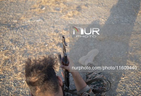 A member of the Islamic Revolutionary Guard Corps (IRGC) holds an AK-45 rifle while preparing to take part in a war game, which is a reconst...