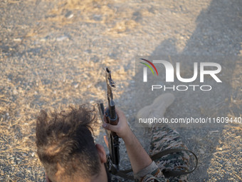 A member of the Islamic Revolutionary Guard Corps (IRGC) holds an AK-45 rifle while preparing to take part in a war game, which is a reconst...