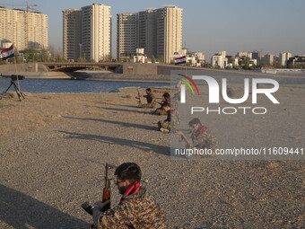 Members of the Islamic Revolutionary Guard Corps (IRGC) hold AK-45 rifles while preparing to take part in a war game, which is a reconstruct...