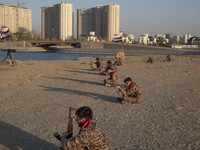 Members of the Islamic Revolutionary Guard Corps (IRGC) hold AK-45 rifles while preparing to take part in a war game, which is a reconstruct...